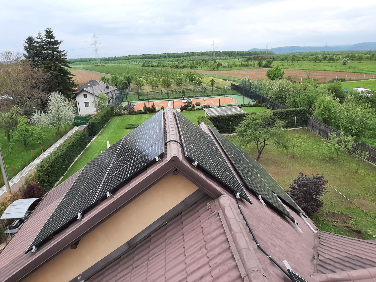 Panouri fotovoltaice pe acoperiș cu vedere spre teren de tenis